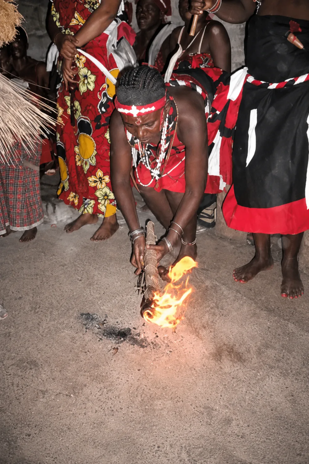 An initiate lights the ritual fire at the heart of the night ceremony, the community gathered around