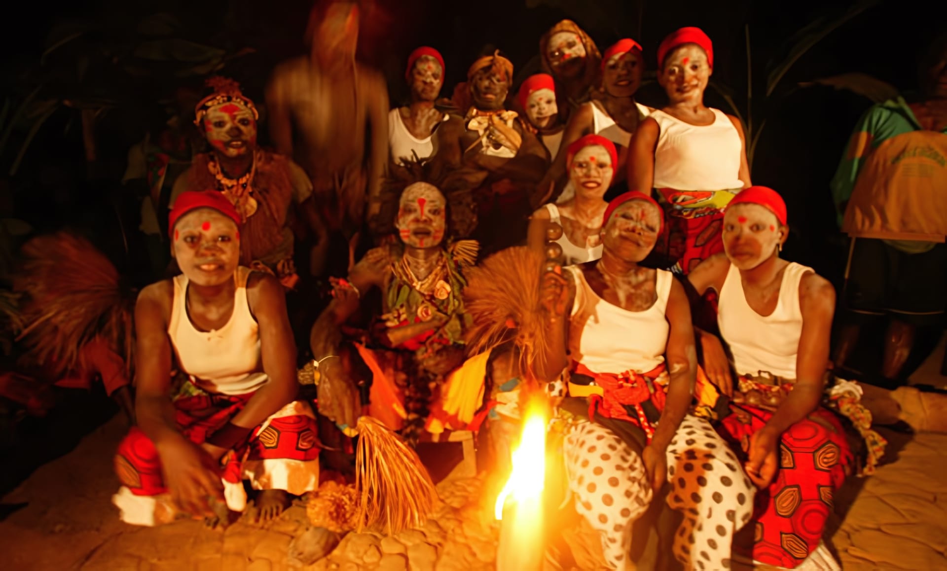 Initiées aux visages peints réunies autour du feu lors d'une cérémonie nocturne à Ebando