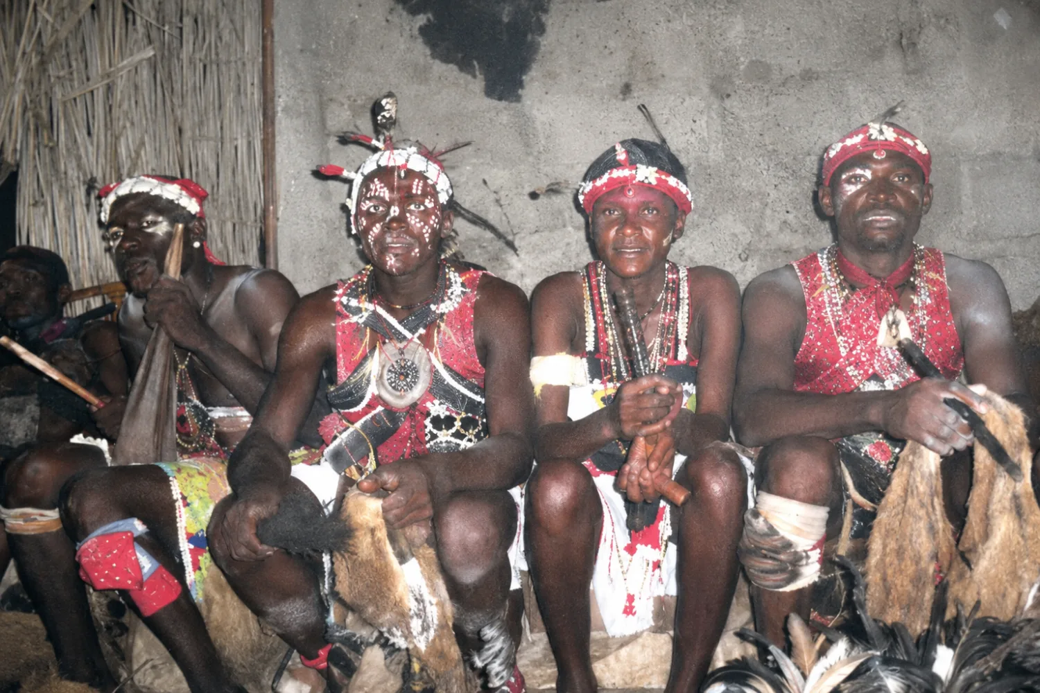 Des hommes assis, le corps peint et orné de plumes, avant la cérémonie