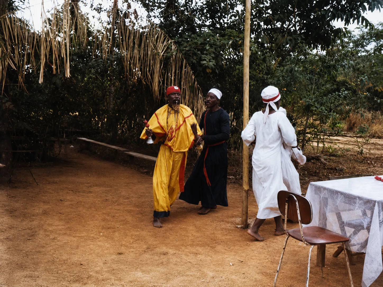 Trois célébrants en boubous lors d'une fête de jour, sur la terre rouge
