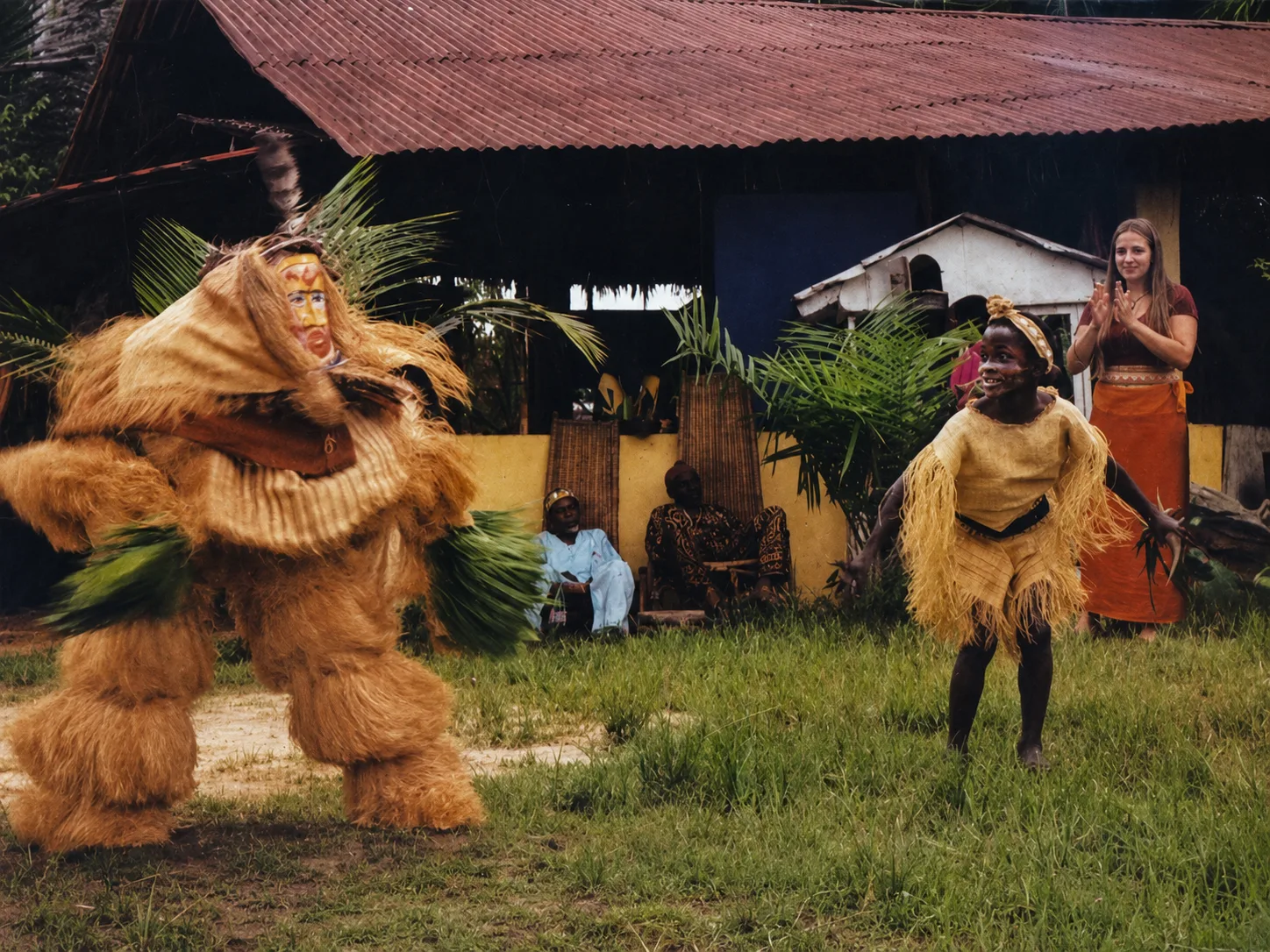 Danse du masque de raphia dans la cour d'un village, devant la communauté