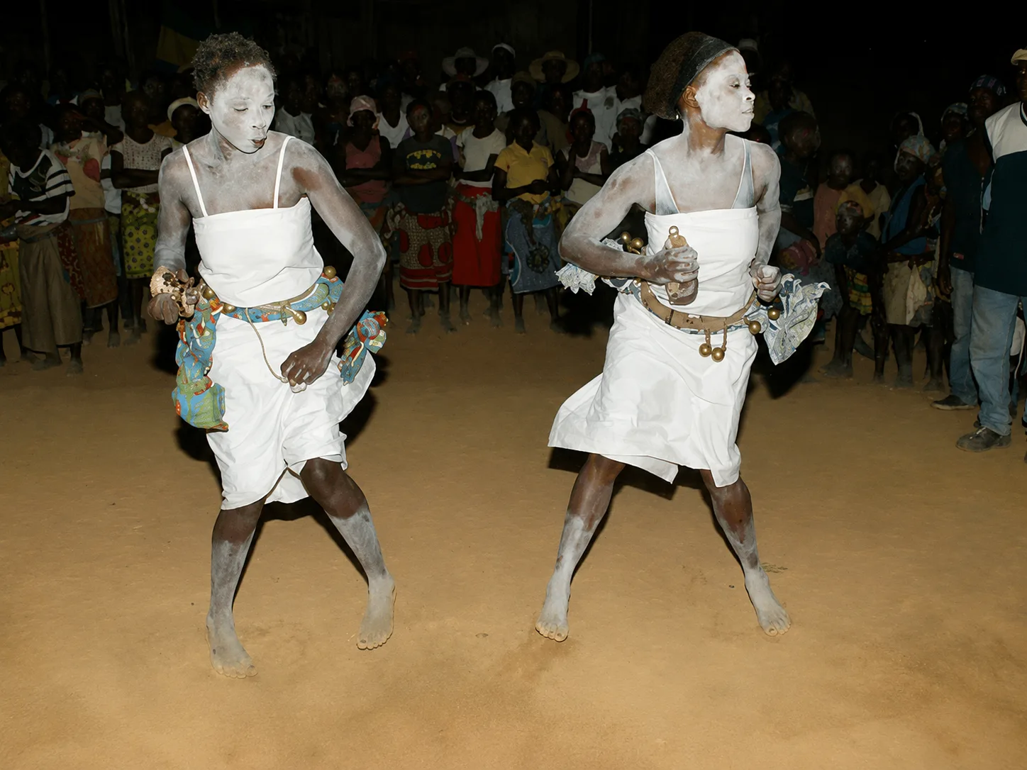 Danse en blanc, grelots aux chevilles, devant le public, la nuit