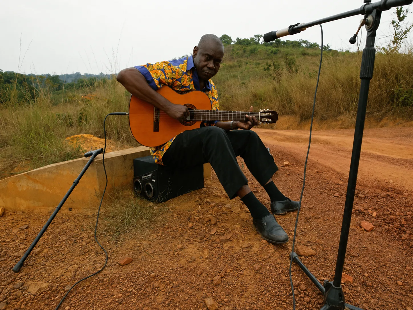 Un musicien joue de la guitare en plein air, devant les collines